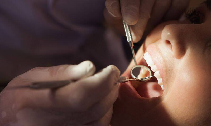 bigstock-Dentist-examining-a-patients-t-71349202