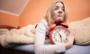 bigstock-Unhappy-Girl-In-Bed-With-Alarm-77119898