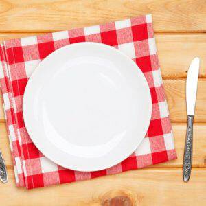 Empty plate, silverware and towel over wooden table background. View from above with copy space
