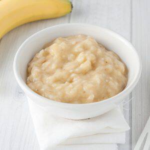 mashed banana in white bowl, baby food, horizontal image